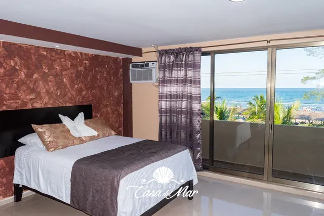 Cama matrimonial con el mar de Tecolutla detrás del ventanal · Hotel Casa del Mar