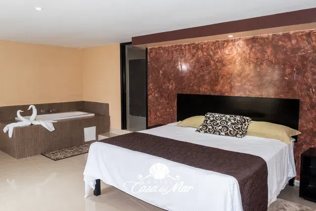 Cama king size con el jacuzzi a un costado, dentro de la suite · Hotel Casa del Mar