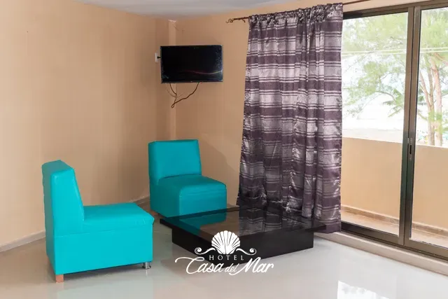 Sala de estar con sillones turquesa junto al balcón · Hotel Casa del Mar