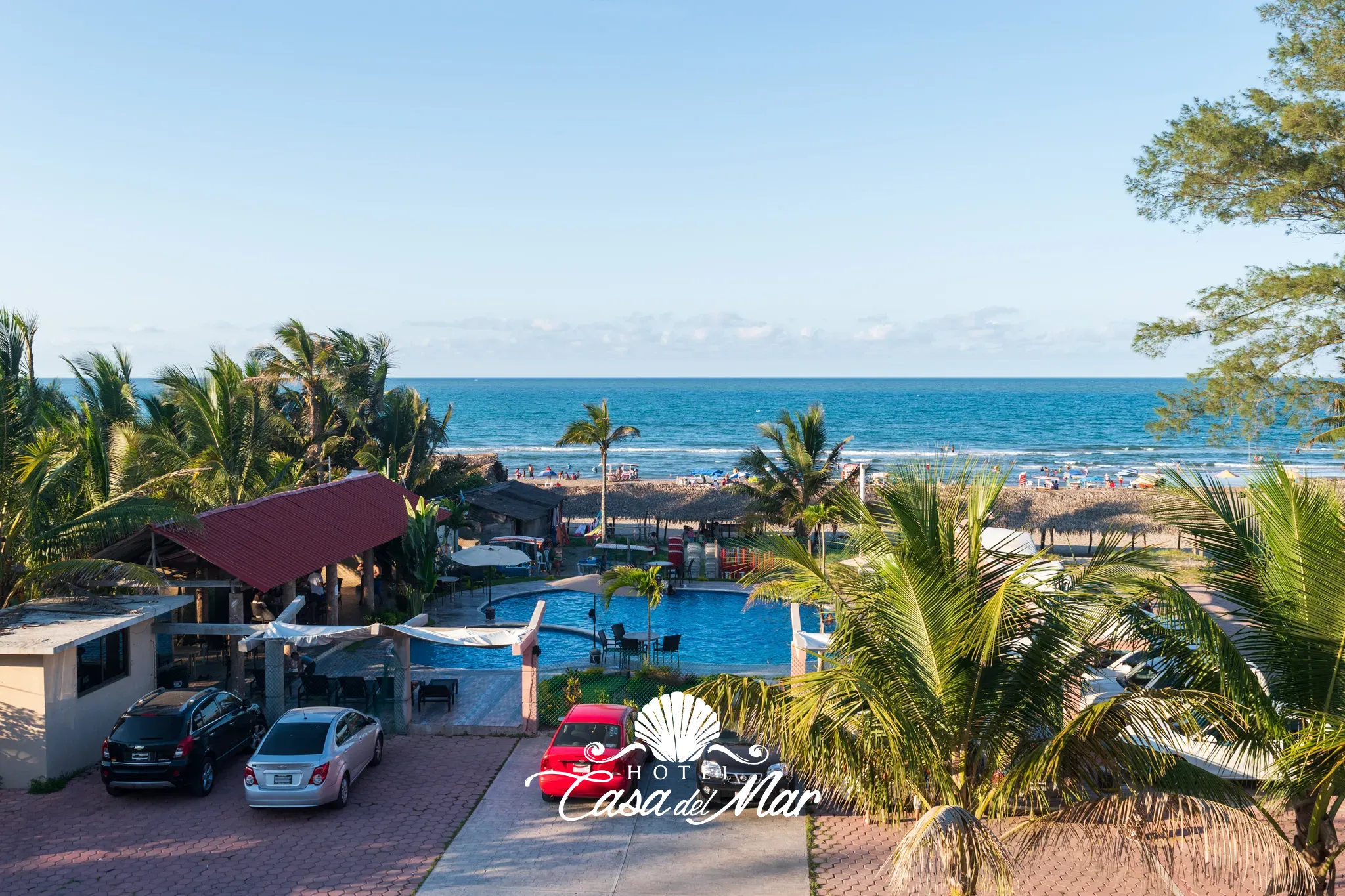Vista desde lo alto del hotel: la alberca exterior, las palapas y el mar a unos pasos · Hotel Casa del Mar